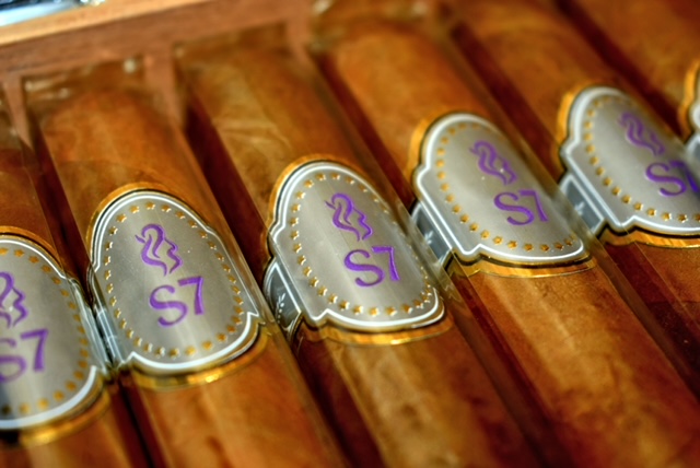 Close-up of SIGARUM 7 S7 bands on a row of cigars in a wooden box